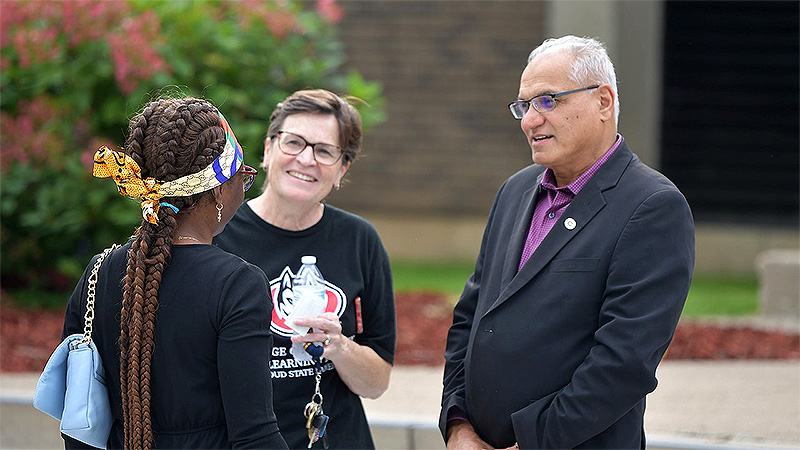Three people talking on St. Cloud State University Campus