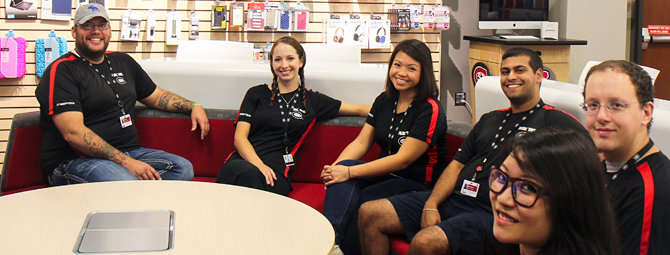 Several HuskyTech students sit together near a round table posing for a group photo