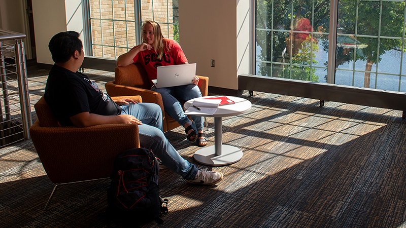 Two students in chairs talking