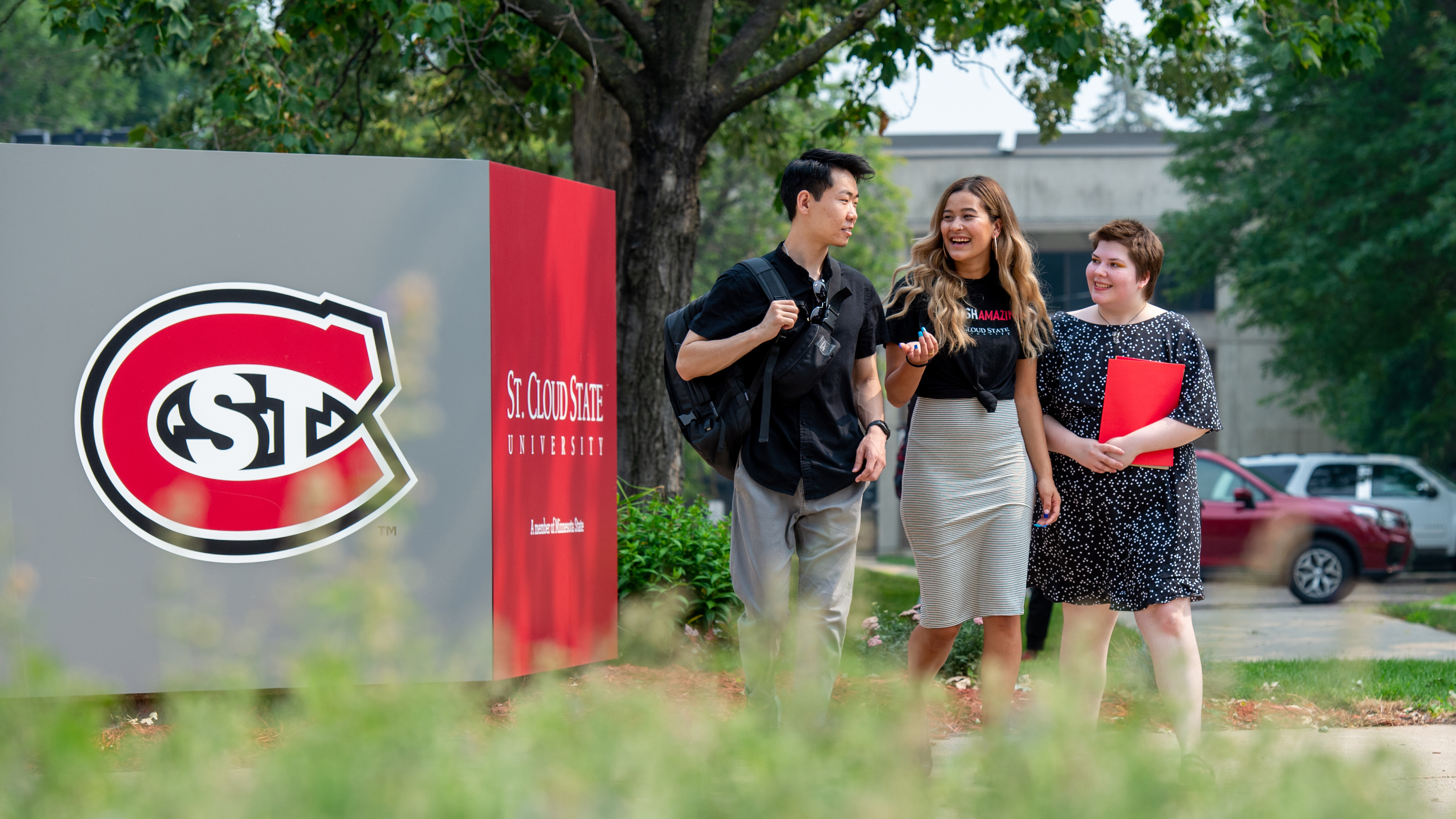 Three students walk to class in front of the Administrative Services Building