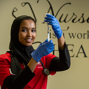 Nursing student filling syringe.