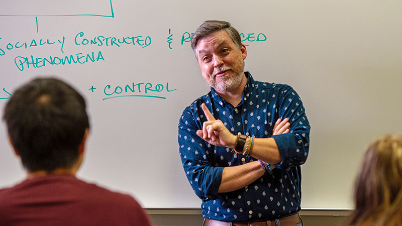 Dr. Michael Dando lectures at the front of a class