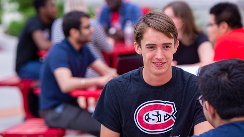 SCSU student studying on outdoor patio table