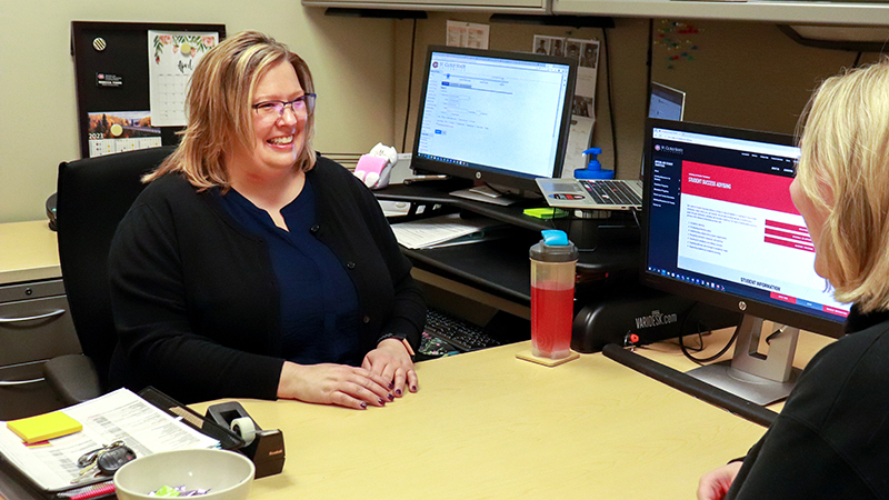 An advisor meets with a student in their office