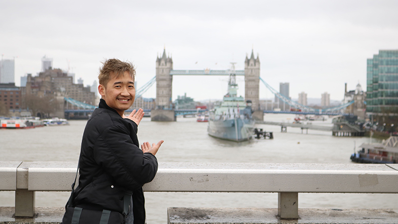 A SCSU student mugs for a photo while gesturing to the Tower Bridge in London