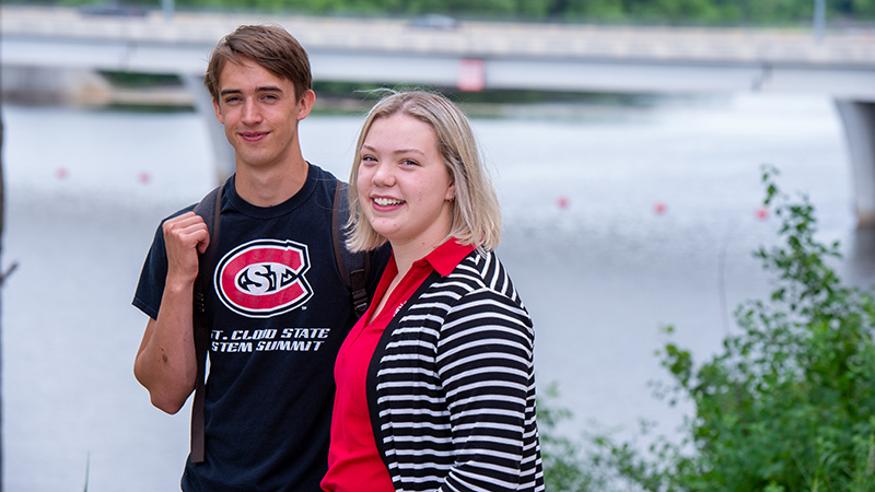 Two SCSU students stand for a photo in front of the Mississippi River on the campus of SCSU