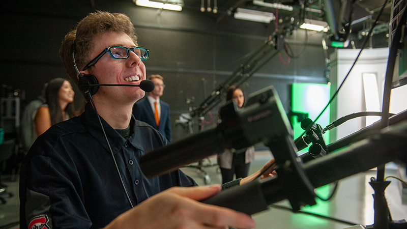 A student operates a TV station camera in the UTVS studios
