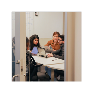 Students seated at a table working together with laptops in an indoor room