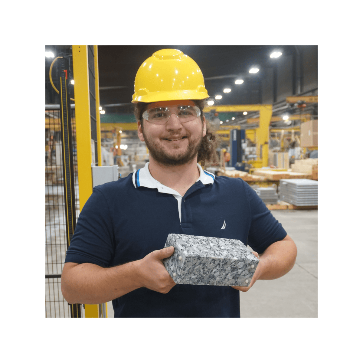 Person wearing a hard hat holding a material sample in an industrial setting