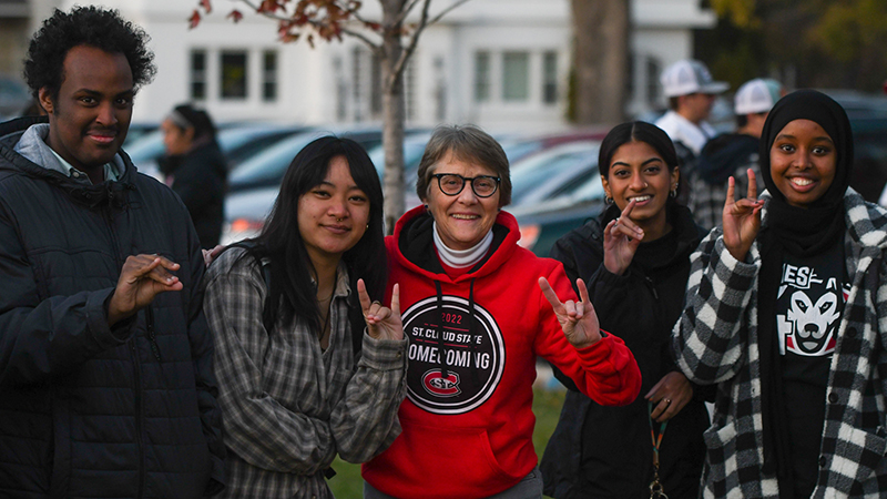 President Wacker doing the sign of the Husky with students