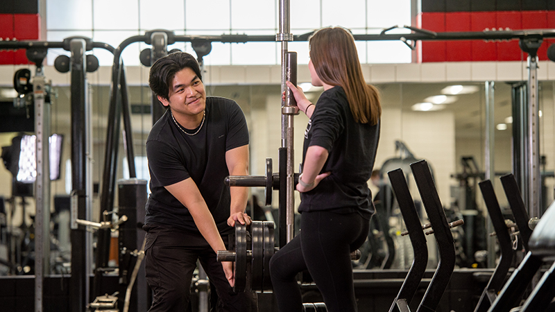Two Huskies lifting weights in Campus Rec weight room