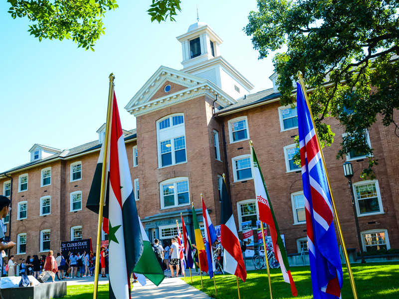 a front exterior view of Lawrence Hall with flags and students visiting