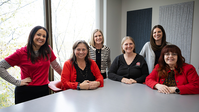 The six Career Center staff members seated at and standing around a conference table