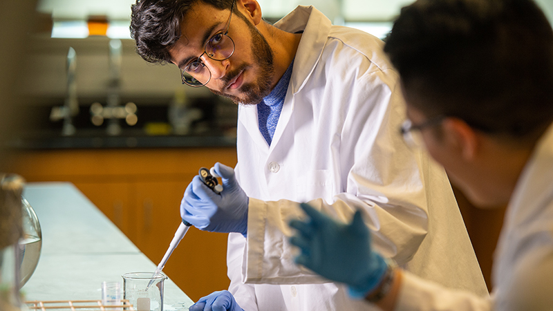 Two students working together in lab with white lab coats