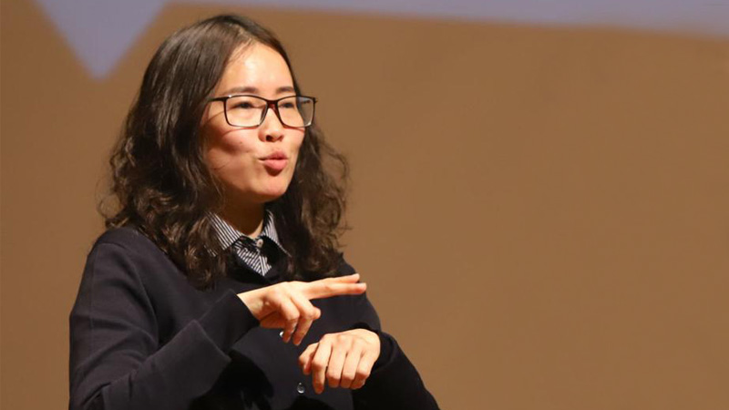 Xiaorong giving a presentation while wearing a black outfit. 