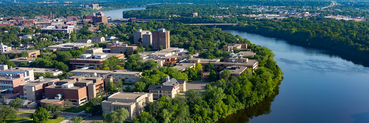 Mississippi river is flowing on the right side next to St. Cloud State University campus. There is a lot of green forest on all sides. 