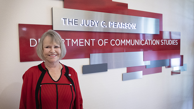 Judy C. Pearson standing in front of new department signage in her name