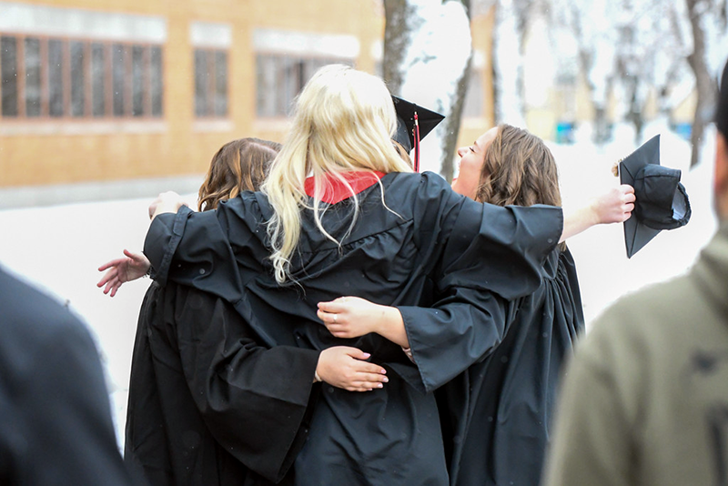 Students and friends hug after graduation