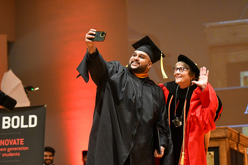 Student takes selfie on stage with Dr. Robbyn Wacker