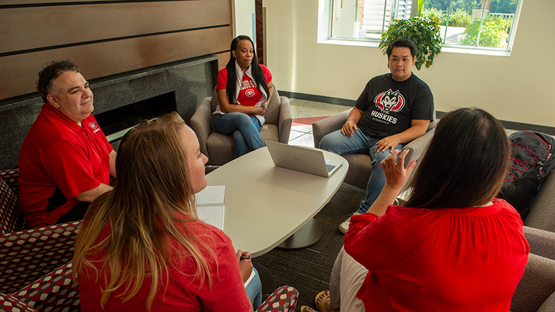 Small group of faculty and students seated in a circle in nice lobby area