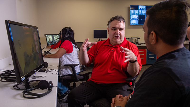 Professor and student seated and talking to one another in observation lab