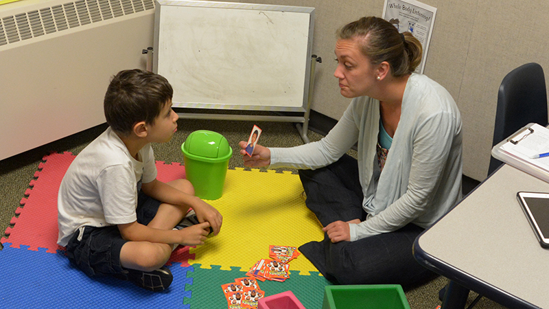 Student working with boy on floor