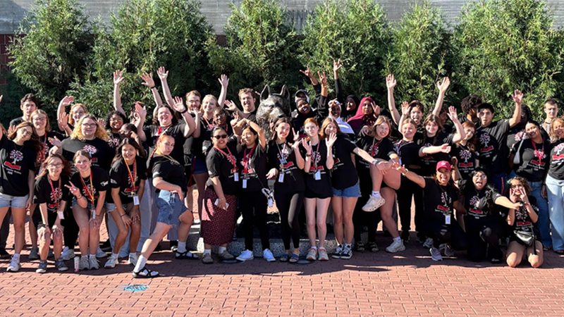 A large group of high school students wearing matching SCSU t-shirts pose for a group on Husky Plaza