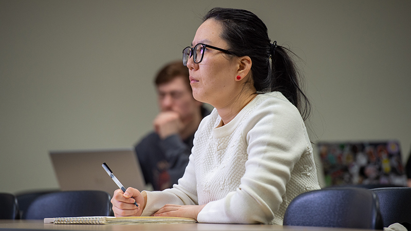 A female student seated in class taking notes