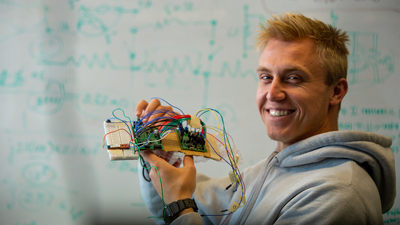 A SCSU student holds computer board and smiles at camera