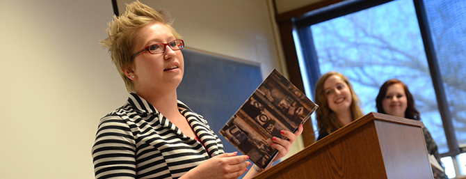 A woman at a podium holding a book