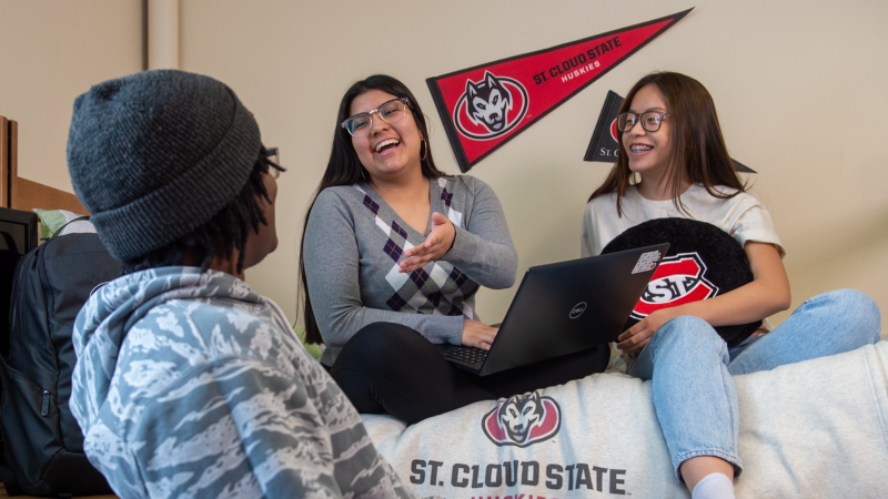 Three students in a residential hall with a computer