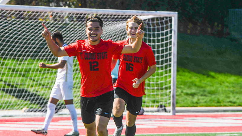 Two SCSU soccer players smiling on the field