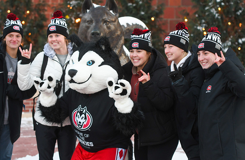St. Cloud State University mascot, Blizzard, with five students making the 'Blizzard' hand sign. 