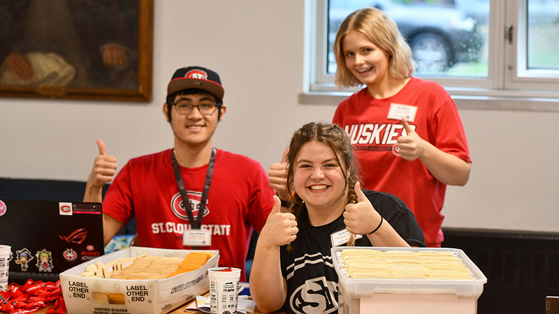 Three St. Cloud State students working a table at an event. 