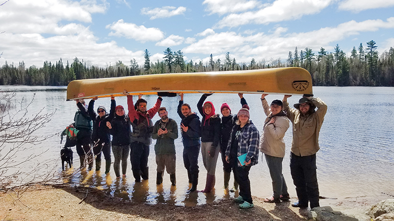 Small group of students holding canoe overhead in Boundary Waters