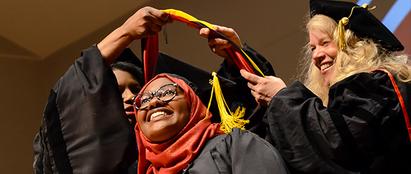 A student receives her graduation hood at the hooding ceremony