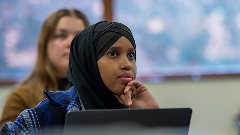 Student wearing Hijab listening to professor in History class
