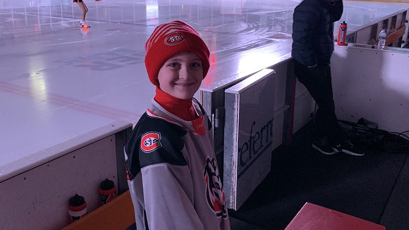 Kid standing by hockey ice