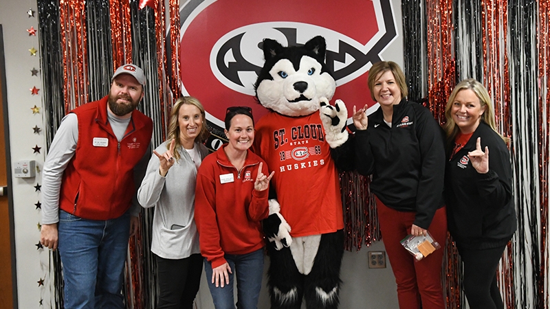Faculty and staff stand in front of office decoration display