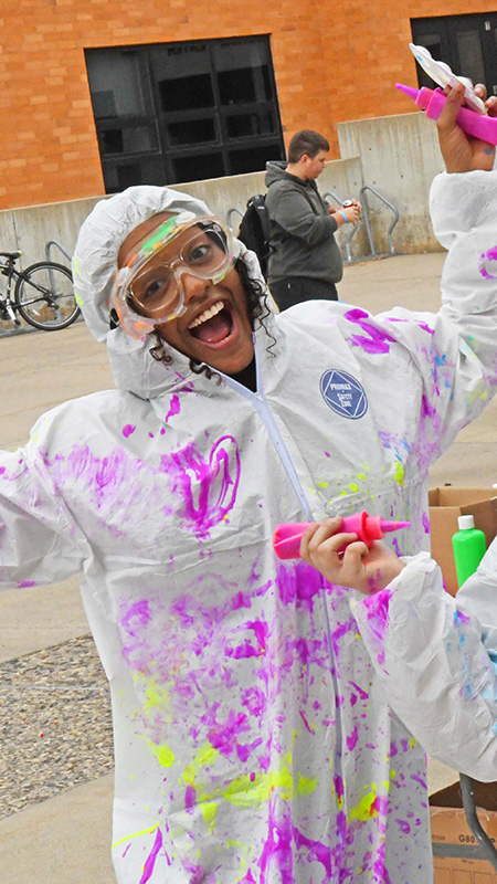 SCSU students wear white jumpsuits as they cover one another in paint at a Homecoming kick-off event