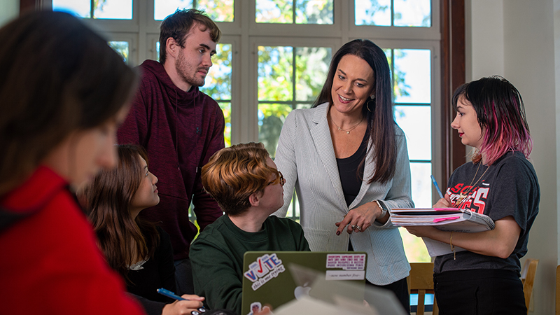 An honors college faculty speaks casually with a small group of honors students