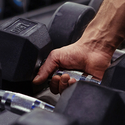 A close up of a hand gripping onto a black dumbbell weight.