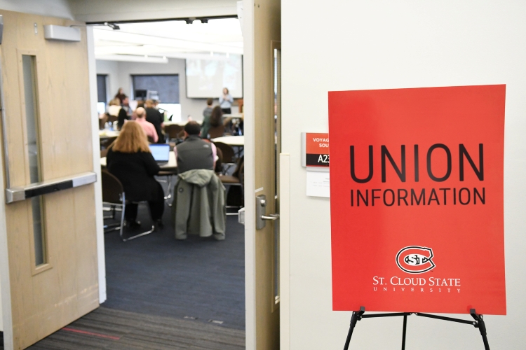 Hallway view of a busy room with a sign that reads "Union Information" outside of it.
