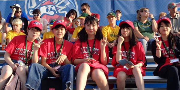 International students sitting in the bleachers of a St. Cloud Rox baseball game