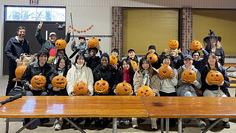 Group of international students carving pumpkins for Halloween