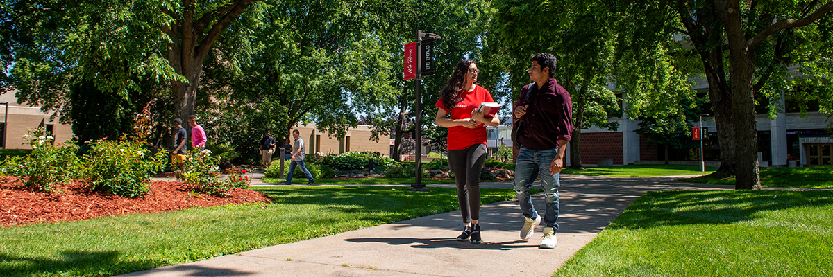 Two students walking with books in hands