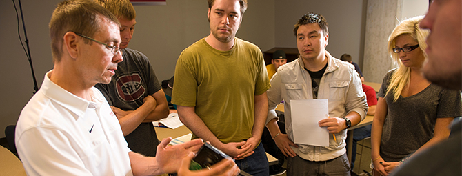St. Cloud State students huddle around a professor while he teaches.