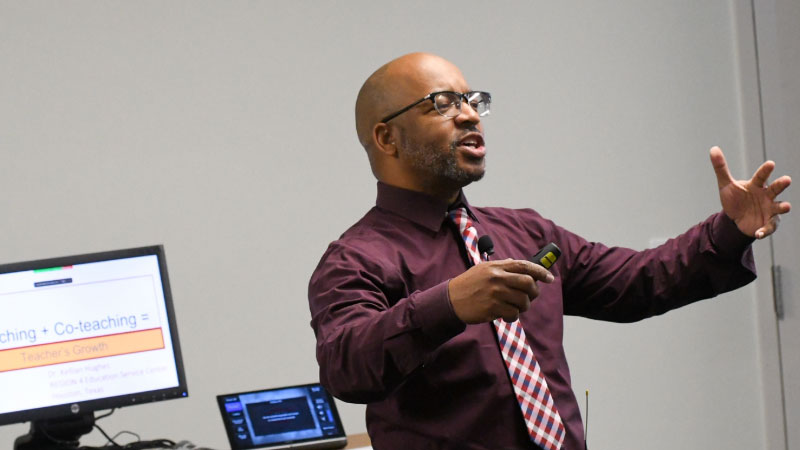 Faculty member wearing a tie while presenting in front of a computer screen