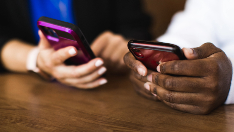 Two sets of hands each holding a cell phone