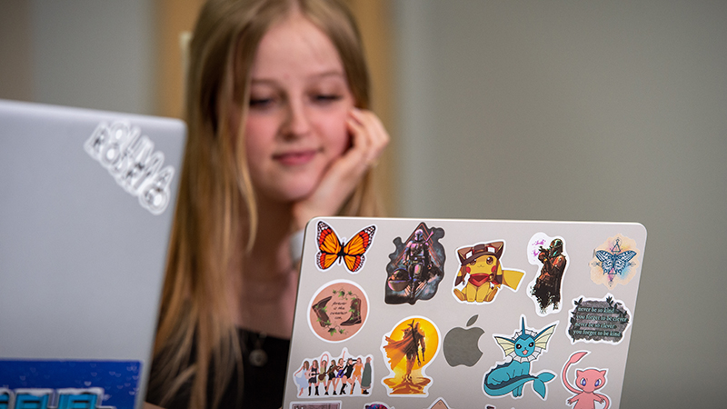 Student on laptop covered in fun stickers